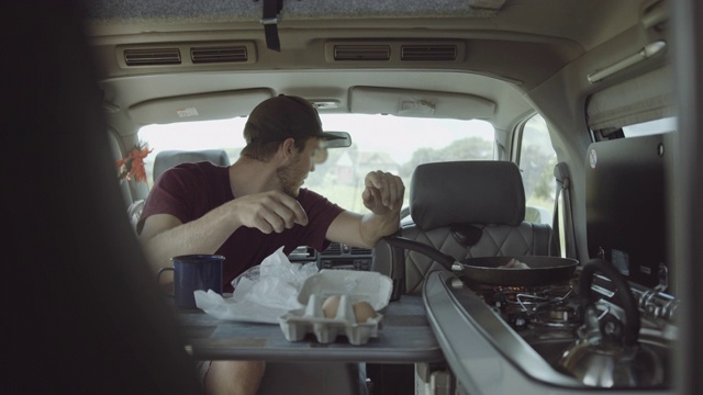 一对年轻的夫妇在露营车上烹饪全英式早餐视频素材
