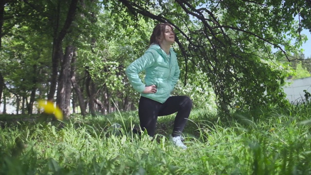 年轻女子训练。妇女在春天的公园里，在开花的树旁做运动视频下载