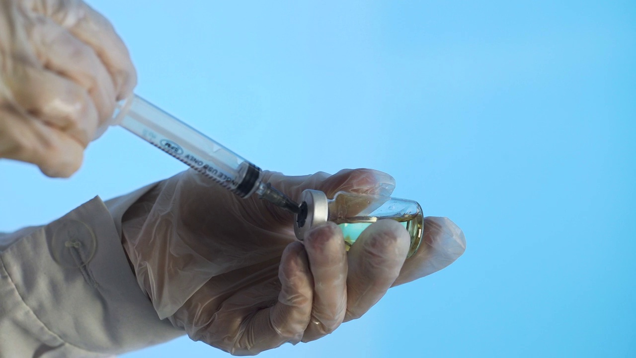 注射器针头刺穿玻璃瓶的橡胶塞，从玻璃中注入注射器视频素材