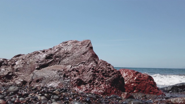 红色的岩石和海浪在圣托里尼红色海滩上溅起水花视频素材