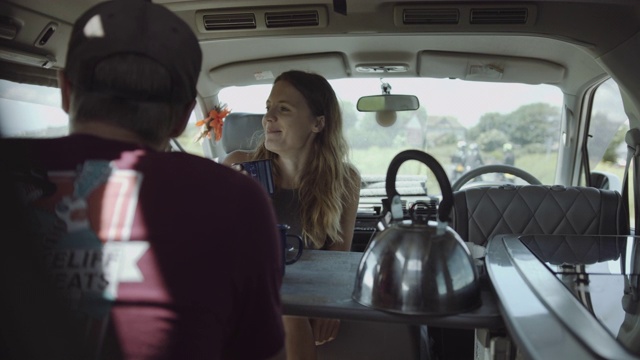 年轻的成年夫妇在露营车里吃早餐和喝咖啡在夏季公路旅行视频素材