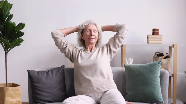 安静的中年老奶奶坐在舒适的沙发上，感觉很放松。视频素材