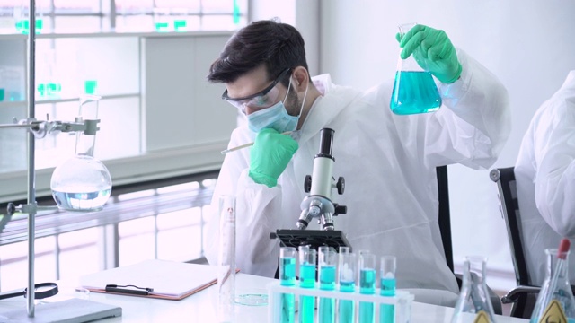 男性科学家实验室技术员分析瓶中的液体视频素材