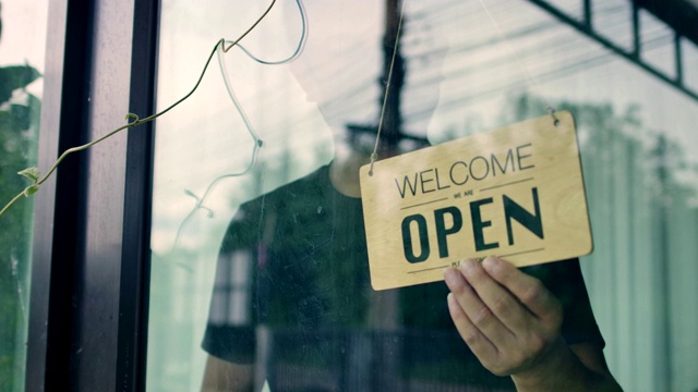 人与服务理念，小企业。亚洲男子戴面具，门上或窗户上挂着“开门”字样的横幅，表示“开门营业”，“随时服务”，有货视频素材