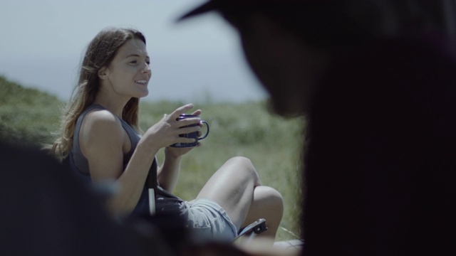 年轻的成年女性在公路旅行中喝着咖啡，在露营车外和男性男友聊天视频素材