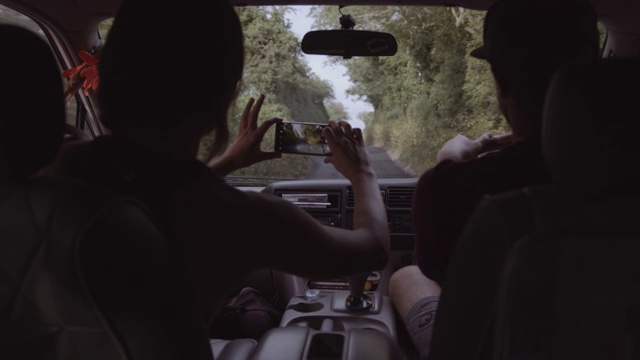 年轻的成年夫妇驾驶露营车公路旅行和拍摄与智能手机视频下载