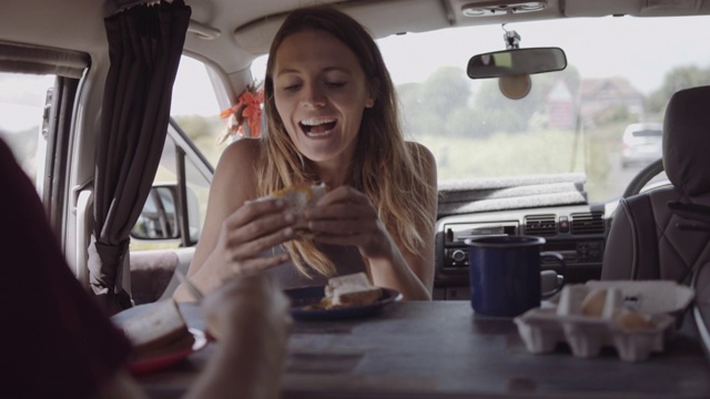 年轻的成年女性在露营车上吃早餐和喝咖啡在夏季公路旅行视频素材