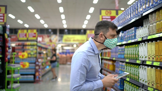 超市员工或老板戴口罩行走和使用数码平板电脑视频素材