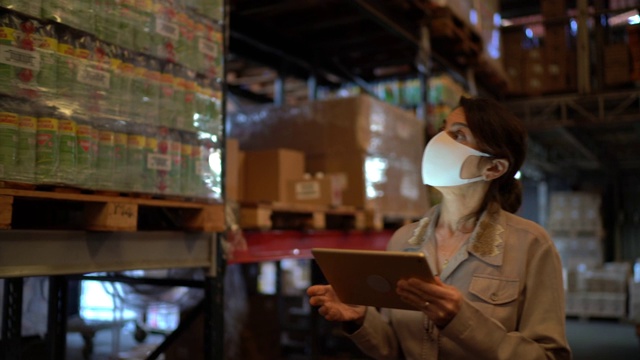女工在仓库边行走边使用平板电脑——戴着口罩视频购买