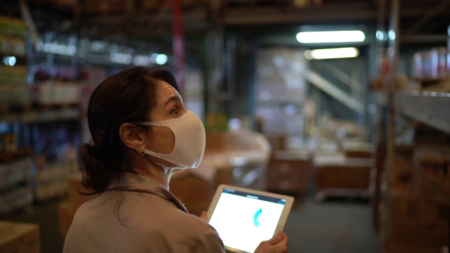 女工在仓库边行走边使用平板电脑——戴着口罩视频素材