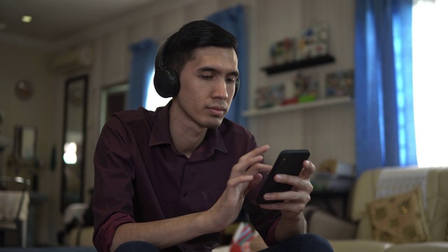 年轻的亚洲男子在家听音乐视频下载