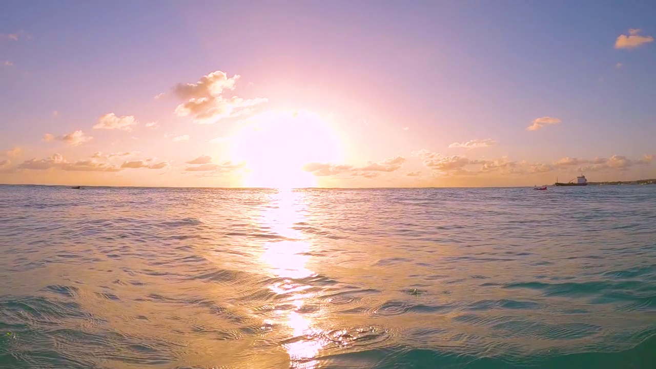 水下:深蓝色的浪花飞溅在拍摄日落的相机上。视频下载