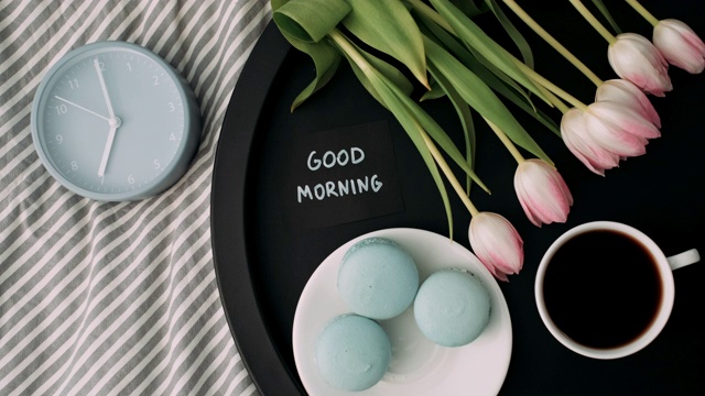 “早上好”，托盘上有法国马卡龙和新鲜郁金香，一杯咖啡和闹钟视频下载
