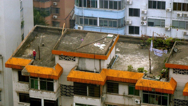 中国广州，一名妇女站在破败的住宅楼屋顶上。视频下载