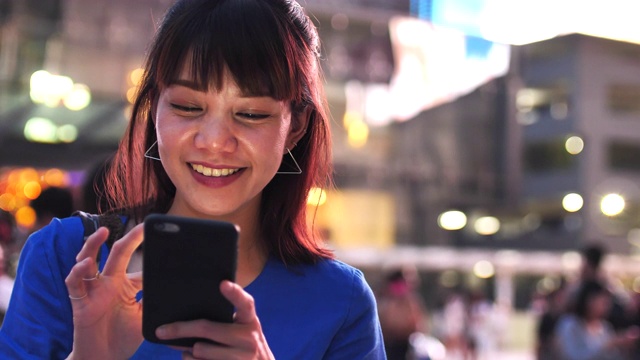 亚洲女性在晚上使用智能手机视频下载