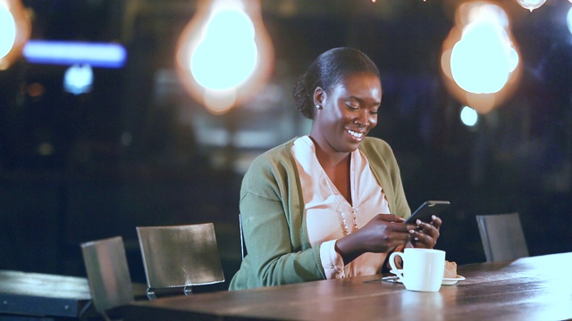 非裔美国女人喝着咖啡，用着智能手机视频素材