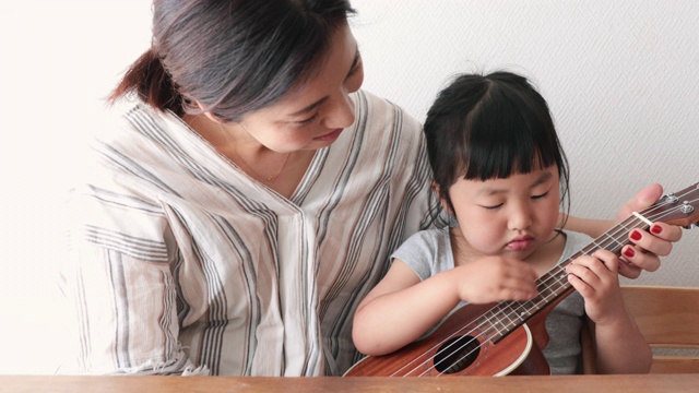 母亲和女儿在家里弹奏尤克里里视频下载
