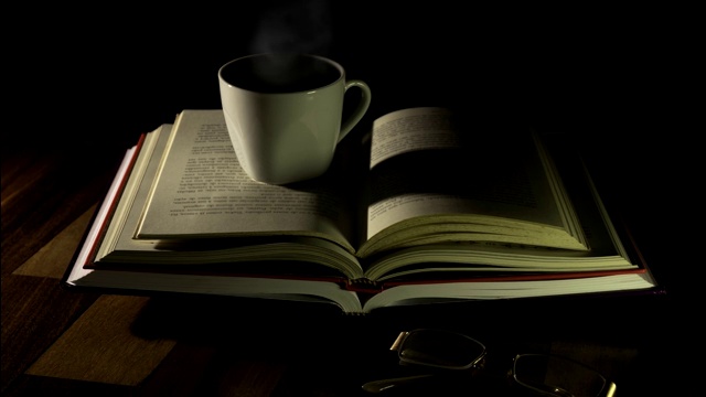 打开书，一杯咖啡和玻璃杯放在木桌上视频素材