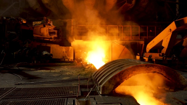 两家炼钢厂在热轧车间电弧炉前铸锭时抖动双手的后视图，冶金生产。资料片。重工业和协议概念视频下载