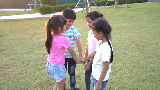 夏日里，一群快乐的亚洲儿童在城市公园的操场上双手摞在一起。儿童与娱乐概念。视频下载