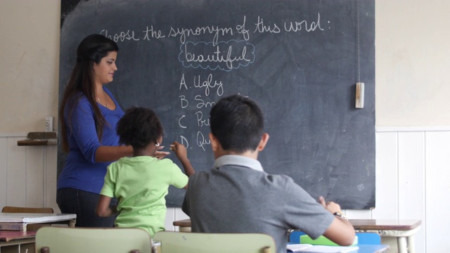 女老师把粉笔递给小女孩，让她在课堂上回答黑板上的问题视频下载