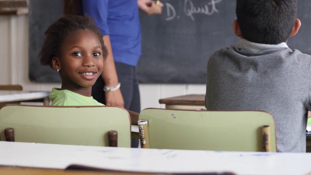 美丽的黑人小女孩面对镜头微笑在课堂上在农村学校视频下载