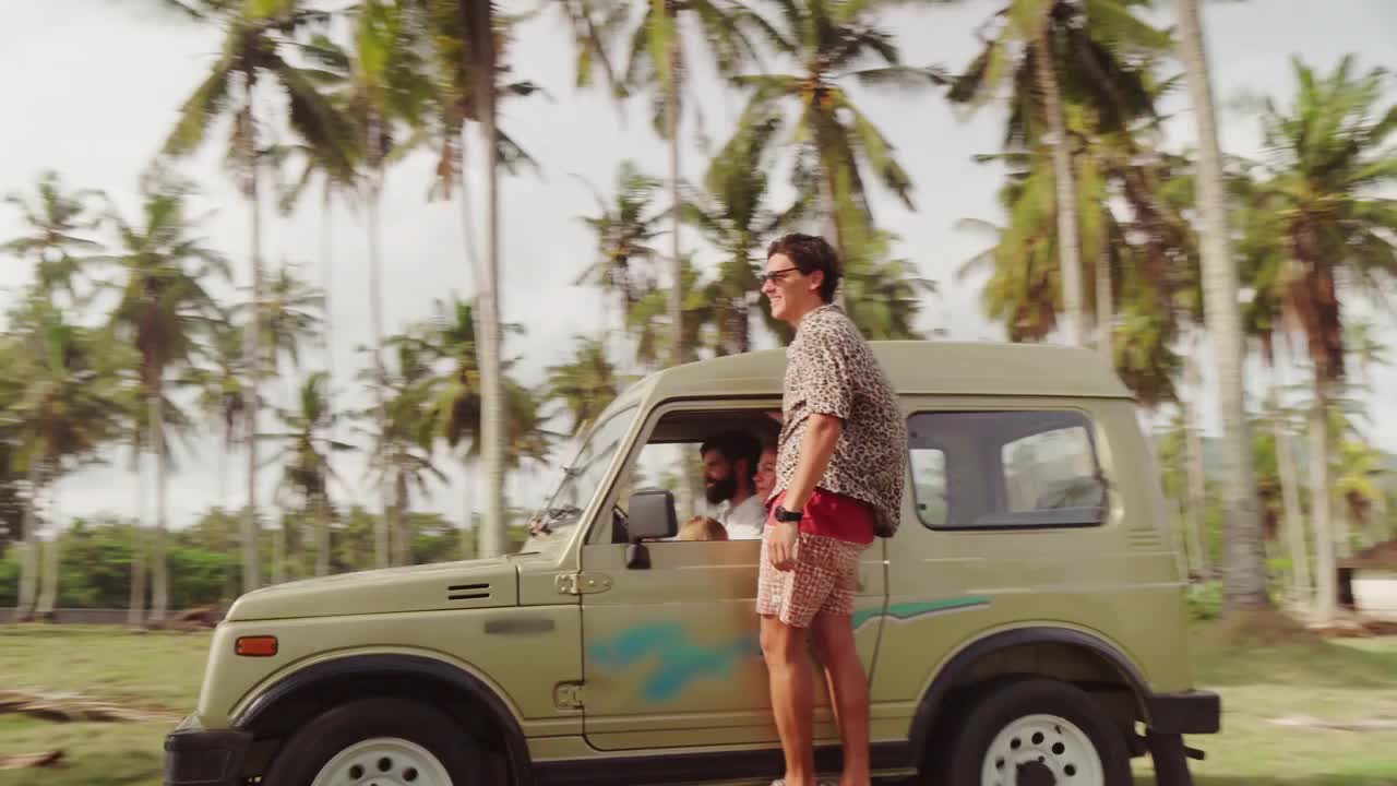 巴厘岛，一名年轻人站在移动吉普车的台阶上视频下载