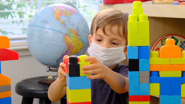 小男孩在幼儿园课桌上戴着防护口罩玩耍视频下载
