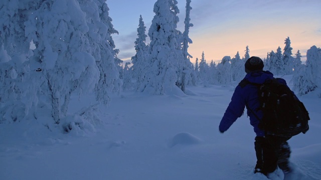 在拉普兰地区，一个背着背包的人在齐膝深的雪地上行走。采用针视频素材