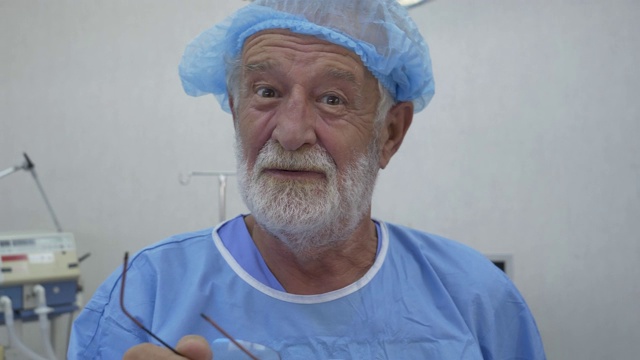 在手术室里，资深男外科医生看着镜头，微笑着说着话。视频素材
