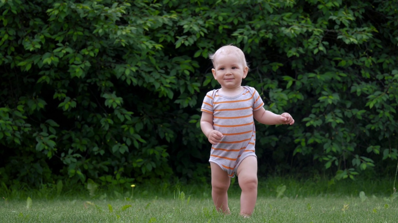 一个快乐的小婴儿在院子里的草坪上迈出了第一步视频下载
