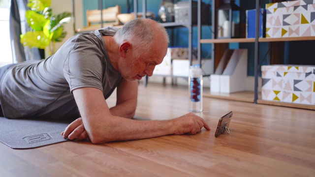 活跃的老年人在家锻炼，看youtube视频，学习锻炼视频素材