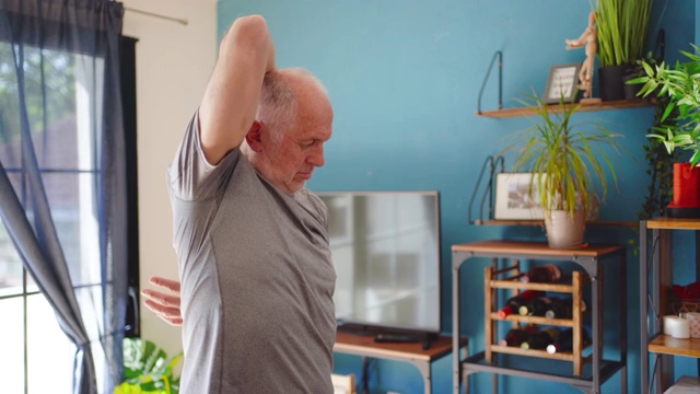 活跃的成熟男子在家里做手臂伸展运动视频素材