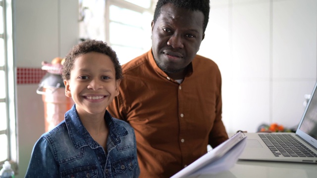 父亲和儿子在家里用笔记本学习的肖像视频素材