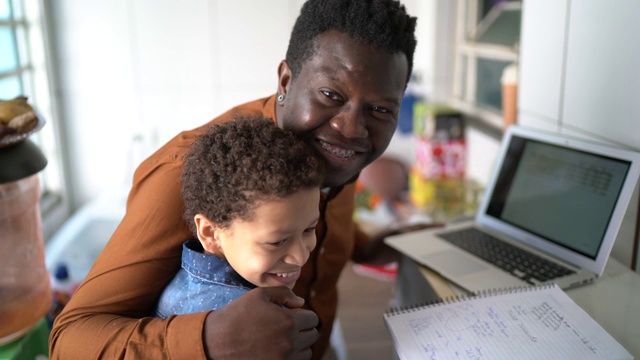 父亲和儿子在家里用笔记本学习的肖像视频素材