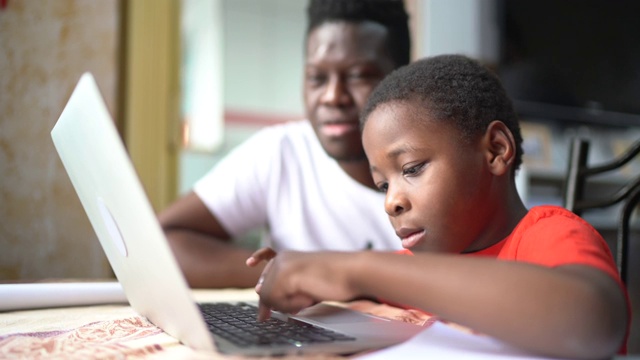 父亲和儿子在家里用笔记本电脑在线学习视频素材