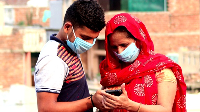 妇女们戴着防病毒的污染口罩，和儿子一起使用智能手机视频素材