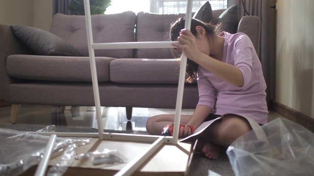 亚洲妇女在家里组装家具视频素材