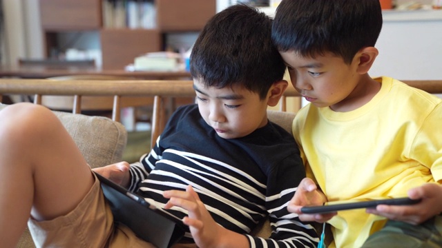 男孩用智能手机和平板电脑玩游戏视频素材
