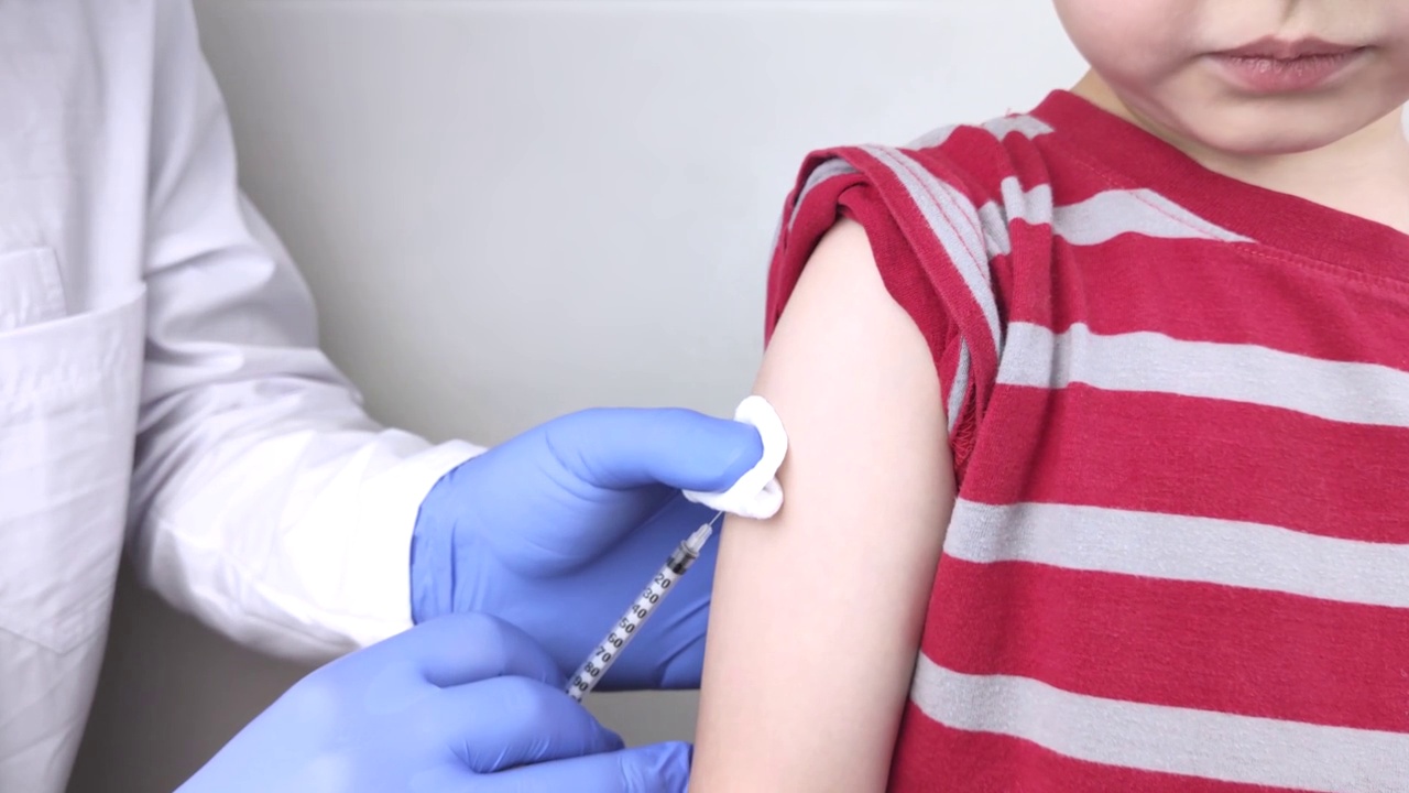 医生给男孩的肩膀注射疫苗。儿童接种疫苗和预防传染病的概念。视频素材