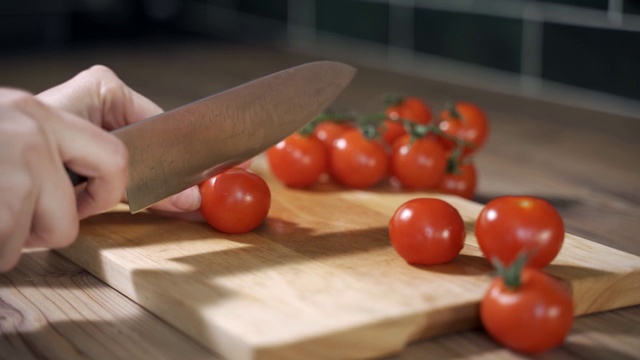 番茄切特写镜头。厨师将樱桃番茄切成片。刀，切菜板，樱桃番茄。视频下载