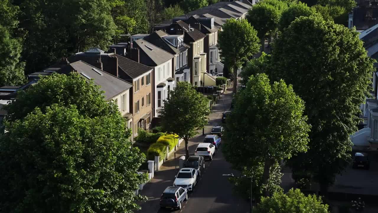 在英国伦敦北部中部，一排排的房子前面停着汽车——高角度无人机拍摄视频素材
