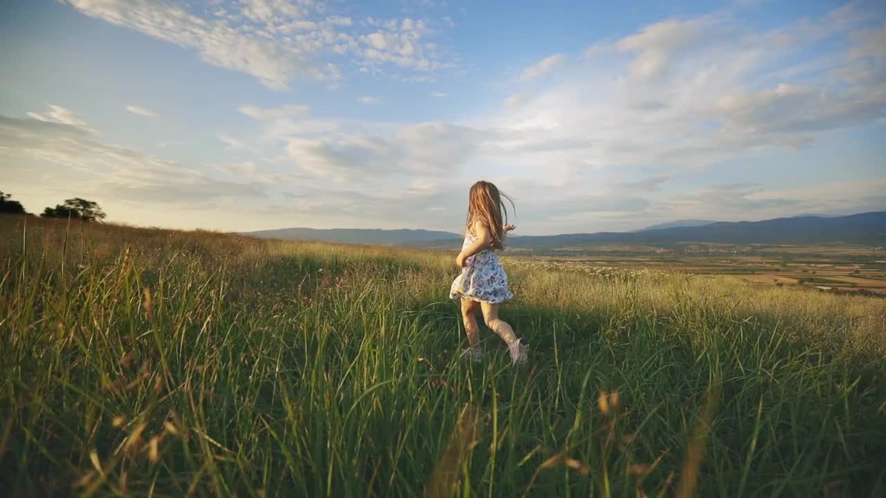 女孩在日落在草地上奔跑-股票视频视频下载