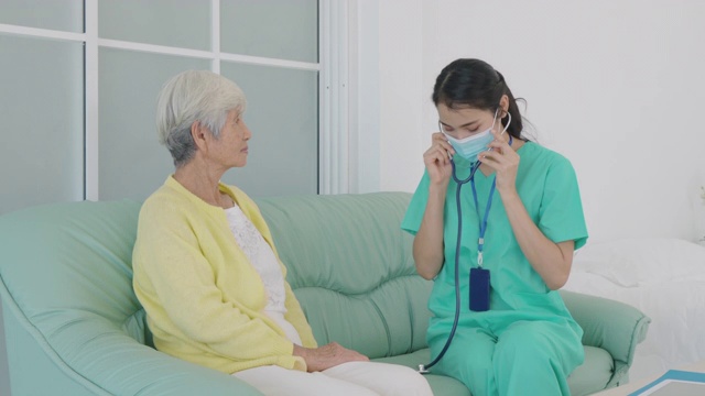年轻的亚洲女护士手持听诊器检查老年老年患者的心跳，在家庭医院进行医疗检查，老年人心脏病保健理念视频素材
