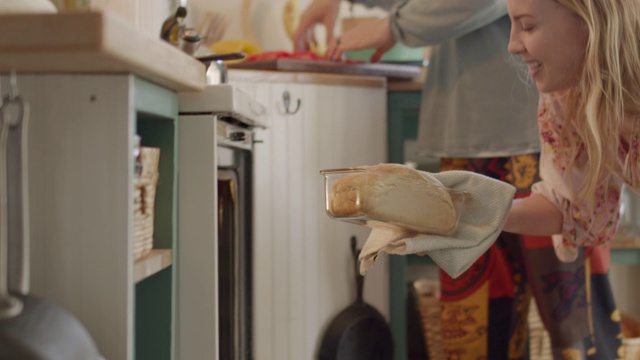 一名年轻女子从烤箱中取出一块刚烤好的面包，放在厨房的柜台上视频下载