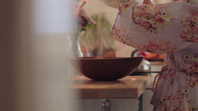 一名年轻女子将面粉从罐子里倒进厨房的碗里视频素材