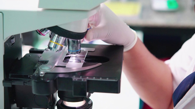 一位女专家正在实验室里操作显微镜。视频素材