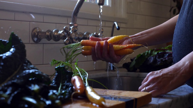 一名孕妇在厨房水槽里洗有机胡萝卜视频素材