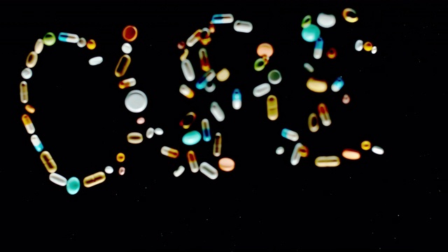 SLO MO LD“CURE”铭文由五颜六色的药片、药丸和胶囊飞向空中视频下载