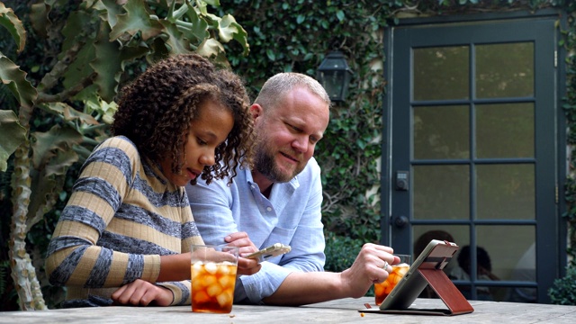 微笑的父亲和女儿在后院看数字平板电脑上的视频视频下载